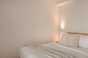 een bed met witte lakens en kussens in een kamer bij Lotus - Unalome Villas in Andipáta Erísou
