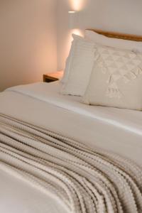 uma cama branca com lençóis e almofadas brancos em Lotus - Unalome Villas em Andipáta Erísou