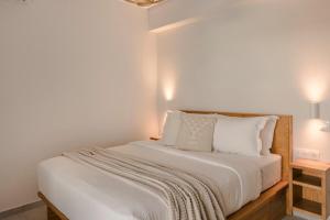 um quarto com uma cama com lençóis brancos e almofadas em Lotus - Unalome Villas em Andipáta Erísou