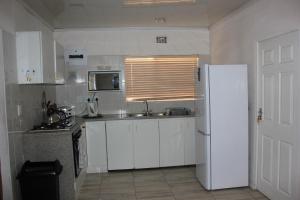 a kitchen with white cabinets and a white refrigerator at Three Arches Guesthouse in Parow