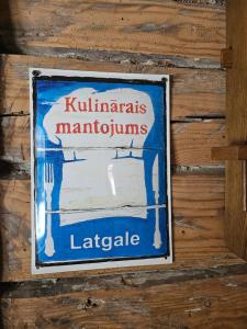 ein Schild an der Seite einer Holzwand in der Unterkunft Zirgu sēta "Klajumi" - Horse ranch "Klajumi" in Kaplava