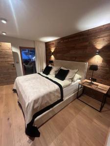 a bedroom with a large bed and a wooden wall at Spa, Sport & City Luxury Ski-in Ski-Out Apartment in Kitzbühel