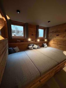 a large bed in a room with two windows at Spa, Sport & City Luxury Ski-in Ski-Out Apartment in Kitzbühel