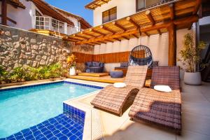 uma piscina com duas espreguiçadeiras ao lado de uma casa em Hotel Bem Brasil em Porto Seguro