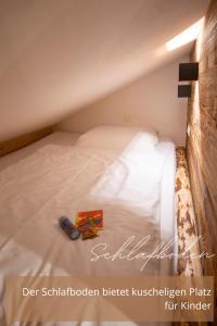 a small bedroom with a bed with white sheets at Zirben -Chalet 1 in Winkl Heiligenblut