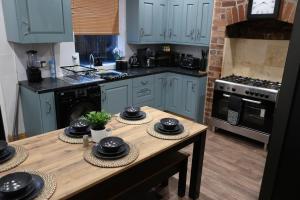 een keuken met blauwe kasten en een houten tafel bij Relax & Unwind In A Stunning 3BD Home in Sheffield in Sheffield