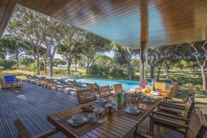 um deque com uma mesa e cadeiras e uma piscina em Villa Golf em Vilamoura
