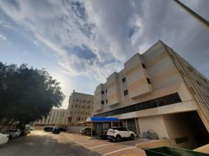 a building with cars parked in a parking lot at الساعه 60 للشقق المخدومه in Dammam
