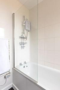 y baño blanco con ducha y bañera. en Large two bedroom Apartment in Cliftonville, en Kent