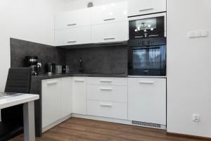 een keuken met witte kasten en zwarte apparaten bij Blue Mare Polanki BeHappy 350 m Baltic Sea in Kołobrzeg