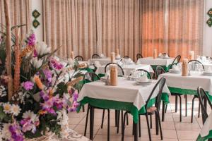 une salle à manger avec des tables blanches, des chaises et des fleurs dans l'établissement HOTEL ITALIACERVIA Free Breakfast, à Cervia