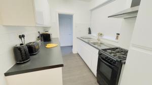 a white kitchen with a black stove top oven at New King-size bed en-suit, luxury refurbished home in Newark-on-Trent