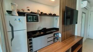 uma cozinha com um frigorífico e uma televisão de ecrã plano em RN Studio Premium em Maceió