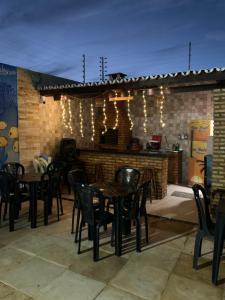 un patio con mesas y sillas y una pared de ladrillo en Happy Hostel e Pousada Paracuru en Paracuru