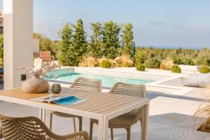 stół i krzesła na patio z basenem w obiekcie Nirvana - Unalome Villas w mieście Andipáta Erísou