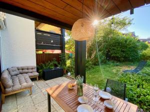 un patio con una mesa de madera y una copa en Snug Stays - Design Studio am See mit Terrasse, Garten, Badestelle vor dem Haus, en Wörthsee
