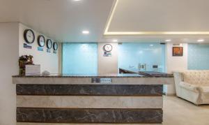 a lobby with a counter with a couch and clocks at Treebo Trend Cordial Home - Jasola in New Delhi