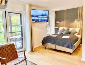 1 dormitorio con 1 cama y TV en la pared en Snug Stays - Design Studio am See mit Terrasse, Garten, Badestelle vor dem Haus, en Wörthsee