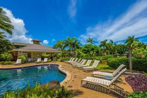 a group of white lounge chairs and a swimming pool at Casa Makara in Princeville