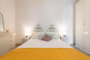 ein weißes Schlafzimmer mit einem großen weißen Bett und einer gelben Decke in der Unterkunft Domo de Maria - Calamenhir in SantʼAntìoco