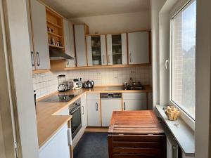una pequeña cocina con armarios blancos y una ventana en Ney-Stay Ferienwohnung en Norderney