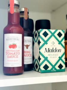 two bottles of hot sauce and a box on a shelf at Gatsby Apartment@Mackay 
