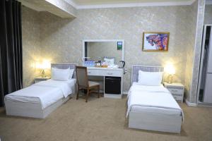 ein Hotelzimmer mit 2 Betten und einem Schreibtisch in der Unterkunft HOBIZ Hotel in Navoiy