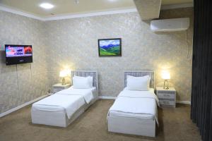 Zimmer mit 2 Betten und einem TV. in der Unterkunft HOBIZ Hotel in Navoiy