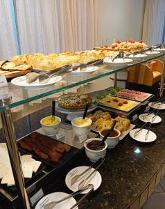 uma linha de buffet com muitos tipos diferentes de alimentos em Golden Hotel em Chapecó