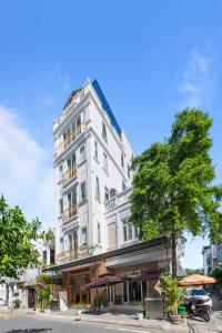 un edificio blanco con un árbol delante en Le's Apartment & Coffee, en Da Nang
