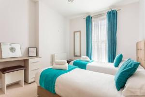 two beds in a bedroom with blue curtains at Castle Haven Apartment Redhill in Redhill