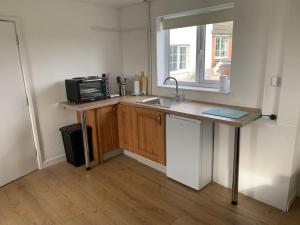 a small kitchen with a sink and a microwave at 1 Bedroom annex, private bathroom, peaceful area in Claypits
