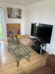 a living room with a tv and a glass table at 1 Bedroom annex, private bathroom, peaceful area in Claypits