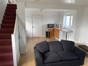a living room with a couch and a staircase at 1 Bedroom annex, private bathroom, peaceful area in Claypits