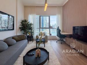 a living room with a couch and a tv at Exclusive Newly Renovated 1BR full Marina views in Dubai