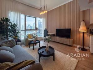 a living room with a couch and a tv at Exclusive Newly Renovated 1BR full Marina views in Dubai