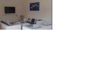 Il comprend un salon doté d'un mobilier blanc et d'une télévision. dans l'établissement Apartamento Frente Rio Una próximo da praia, à São Sebastião