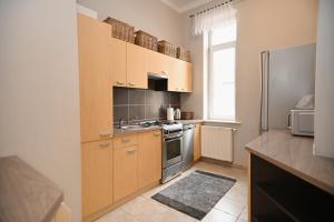 une cuisine avec des armoires en bois et un réfrigérateur en acier inoxydable dans l'établissement Victus Apartamenty, Apartament Tuż Przy Plaży, à Sopot