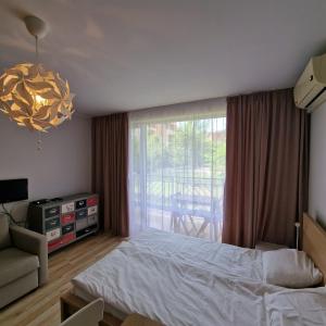 1 dormitorio con cama, sofá y ventana en HOLIDAY ORCHID FORT GARDEN - Premium Apartments, en Sunny Beach