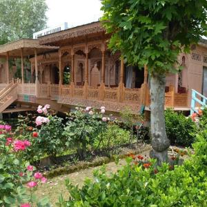 a house with a porch and flowers in a garden at The Heritage Group Of Houseboats in Srinagar