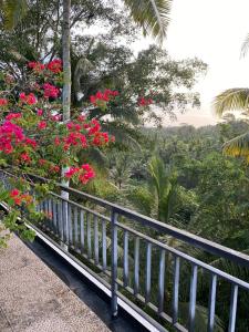 een balkon met rode bloemen en uitzicht op een bos bij Umah Saren Homestay in Undisan