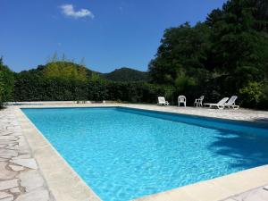a swimming pool with two lawn chairs and two chairs at Apart'Hôtel Les 4 Sources in Anduze