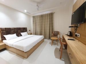 een slaapkamer met een bed, een bureau en een televisie bij HOTEL SCARLET in Gwalior