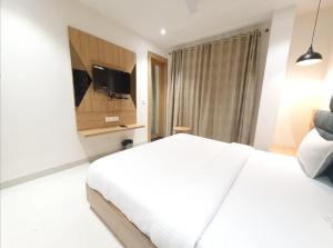 1 dormitorio con 1 cama blanca y TV de pantalla plana en HOTEL SCARLET, en Gwalior