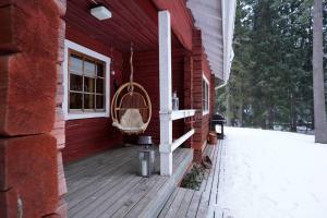 un porche de una casa roja con una jaula de pájaro en Lakeside Rustic Luxury, en Kajaani