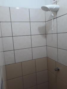 a white tiled bathroom with a shower with a fan at Hotel Gringos in Londrina