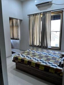 a bedroom with a checkered bed in front of a window at D Villa : A posh bunglow with modern amenities in Panaji