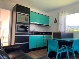 a kitchen with green cabinets and a blue table at Apartamentos de Altitude Urubici in Urubici