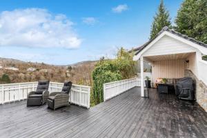een houten terras met stoelen en een prieel bij Cozy house with lovely view in Bergen