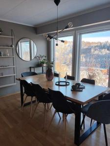 een eettafel met stoelen en een groot raam bij Cozy house with lovely view in Bergen